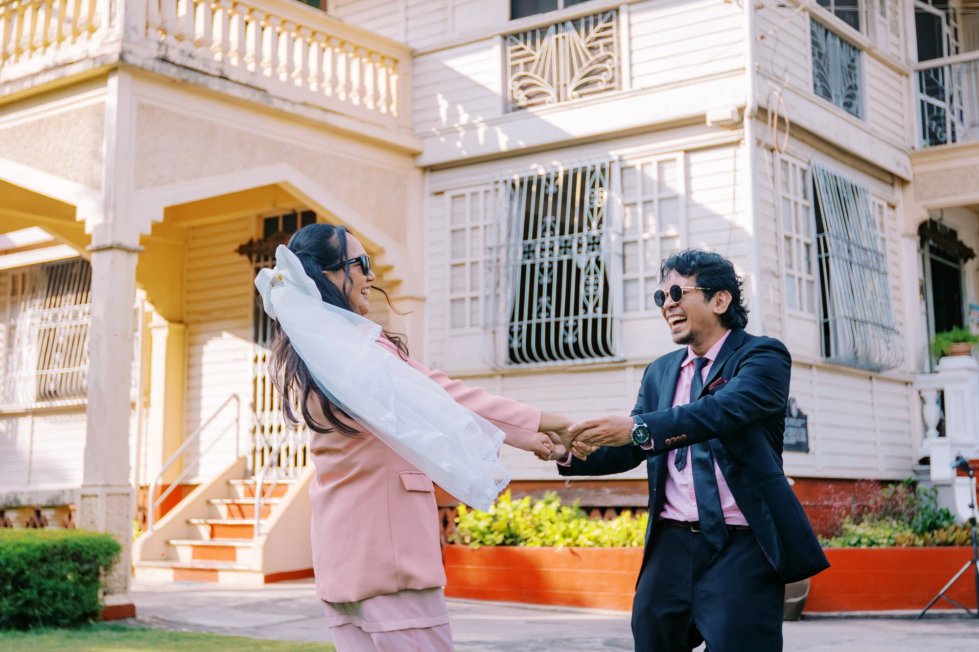 Clive and Rubie laughing and holding hands outside a heritage house