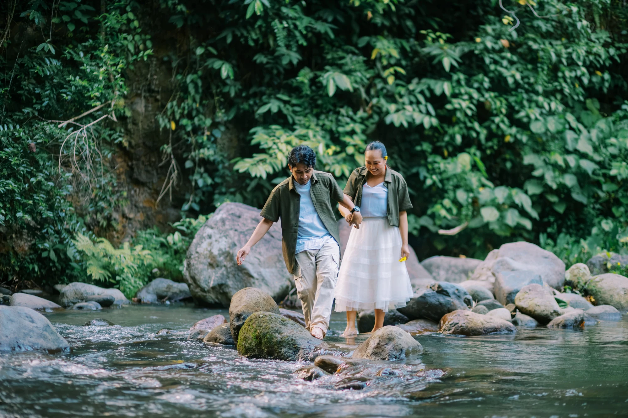 Clive and Rubie walking hand in hand through a leafy river